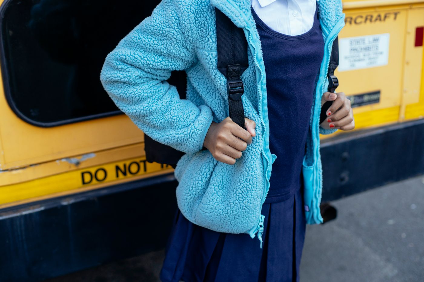 Student with a backpack beside a parked school bus
